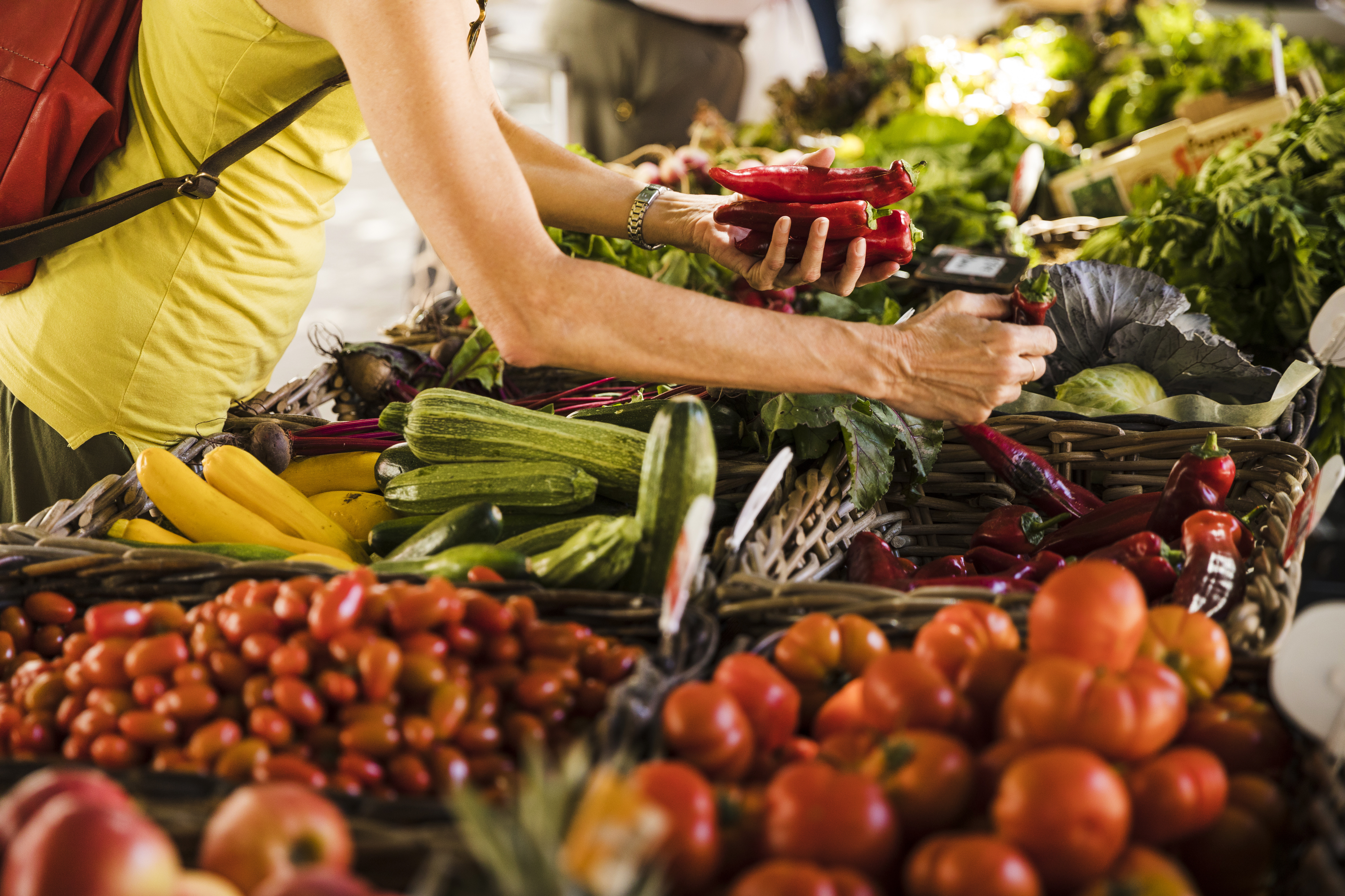 man choosing vegetable from vegetable stall supermarket